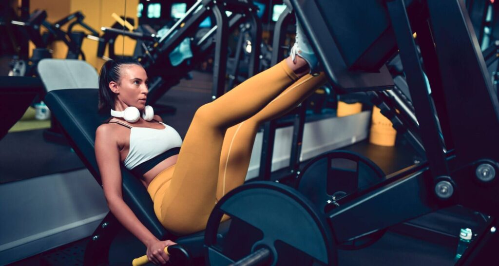 Eine Fitness-Sportlerin trainiert mit hohem Volumen an einer Beinpresse.