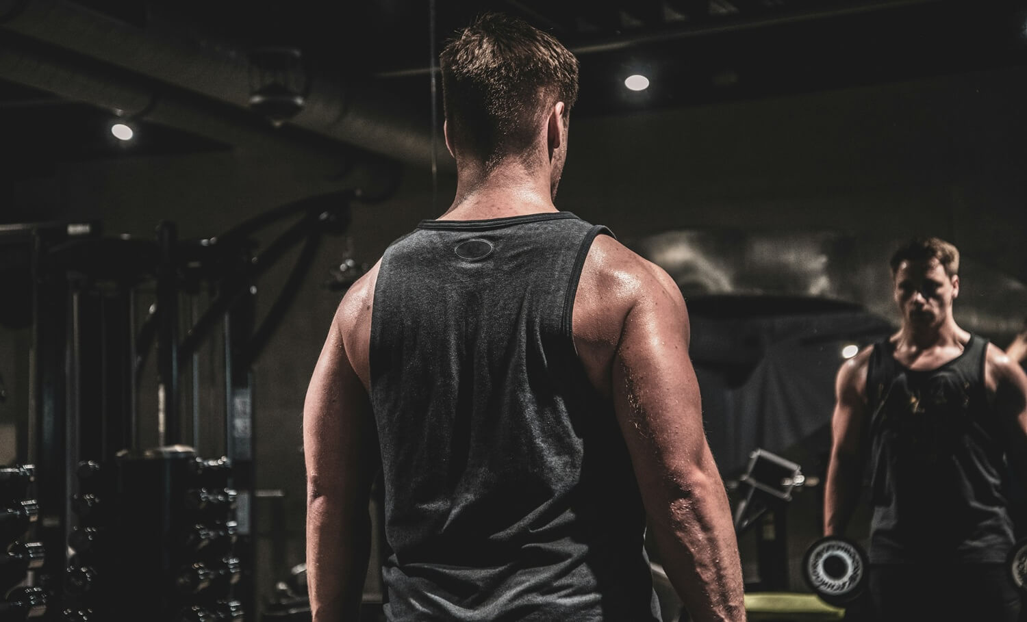 Ein Bodybuilder curlt vor dem Spiegel - selbstverständlich ausschließlich, um die korrekte Ausführung der Übung zu überprüfen.